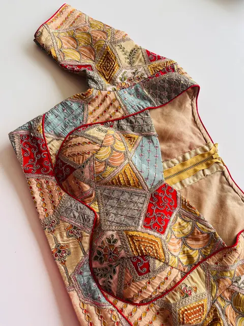 A patchwork blouse in ochre, rust, teal and red, pieced in geometric panels.