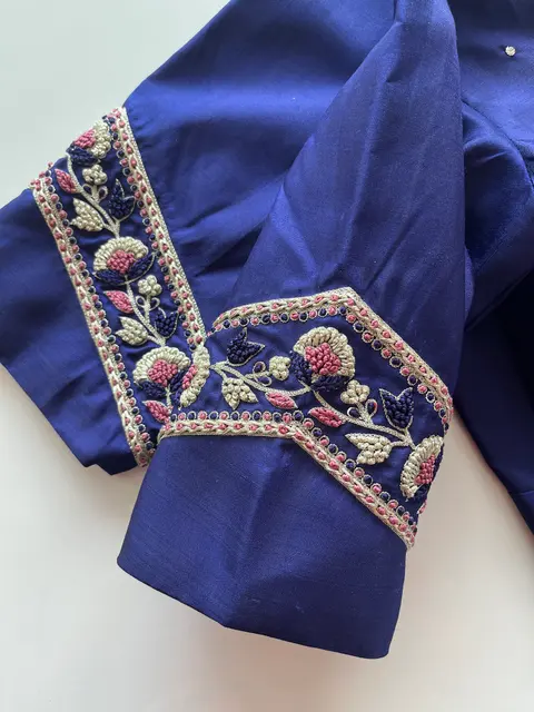 A royal blue blouse with white and rose floral needlework along the neckline and sleeve.