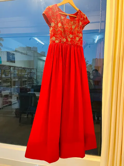 A deep red gathered lehenga skirt hanging in the studio.