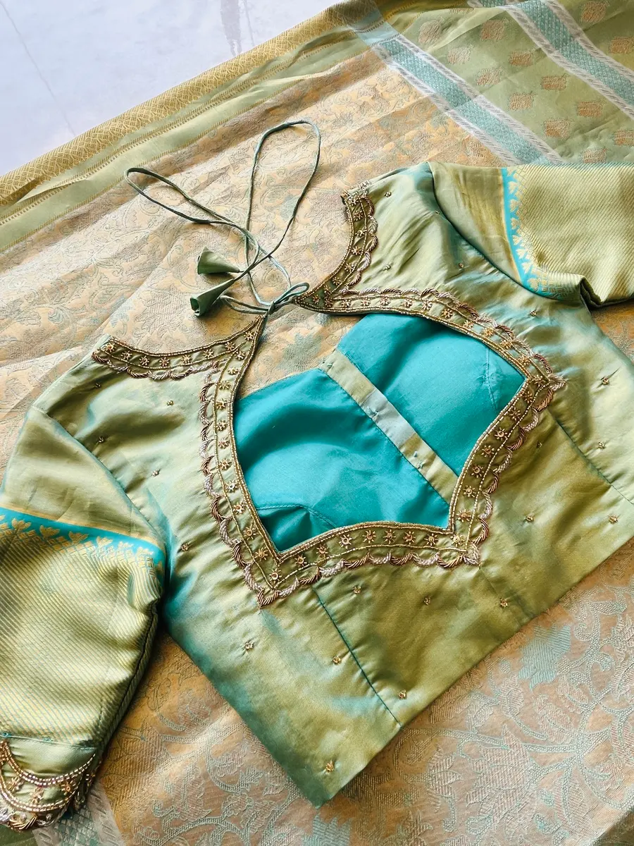 A sage green blouse with a turquoise keyhole back framed in gold aari embroidery.